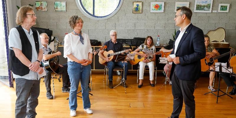 Mehrere Personen, teilweise mit Gitarren in der Hand