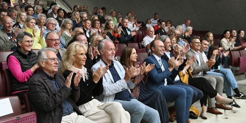 Zahlreiche Theaterbesucher sitzen auf den Rängen