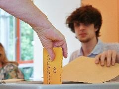 Wähler wirft seine Wahlunterlagen in eine Wahlurne