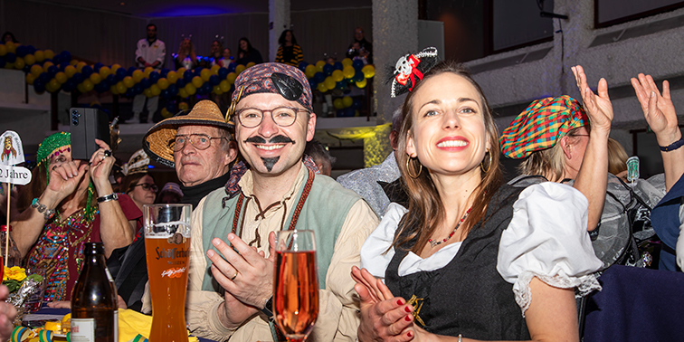 Viele Menschen feiern in einer Festhalle Fasching bei einer Kostüm-Punksitzung.