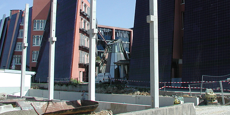 Bauarbeiter mit Schaufel bei Straßenausbesserungsarbeiten; ebenfalls im Einsatz: Bagger und LKW