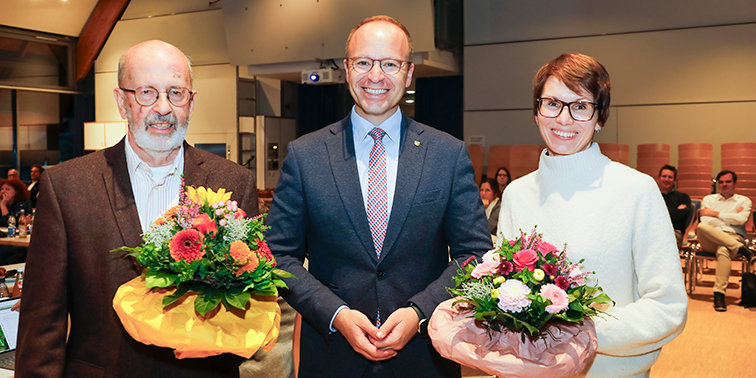 Drei Personen bei einer Ehrung mit Blumensträußen in der Hand