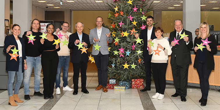 Personengruppe steht rund um einen Weihnachtsbaum