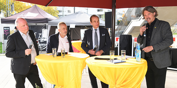 Vier Herren an Stehtischen bei einer Podiumsdiskussion