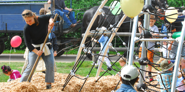Mehrere Kinder spielen in einer Kletteranlage auf einem Spielplatz.