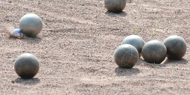 LE, sportlich gesehen Silberfarbene Boulekugeln auf sandigem Spieluntergrund